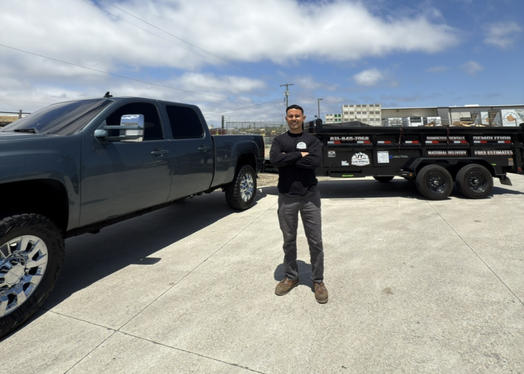 Oscar standing beside his pickup truck and JT Junk Removal trailer